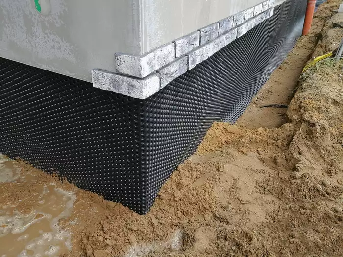 Black plastic drainage membrane fixed on the foundation of house under construction